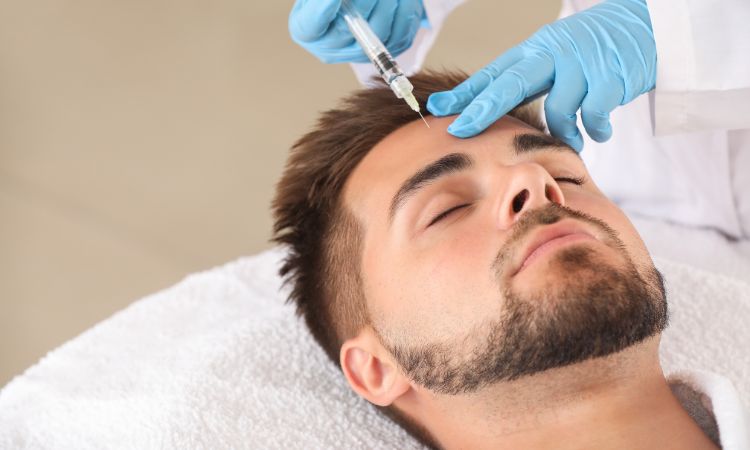 Hombre recibiendo tratamiento estético con inyección en la frente durante una sesión de medicina estética.